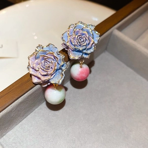 Macro shot of rose flower earrings with gradient pearls on a gray velvet tray