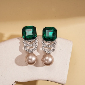 Vintage green crystal and champagne pearl drop earrings on white stone display