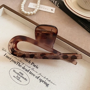 Detailed view of amber leopard print hair claw clip on an elegant tray with pearls
