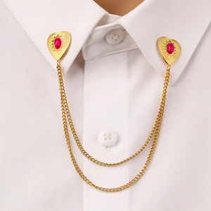 Golden heart collar pin with red gemstones and double chain on a white shirt