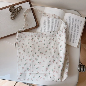 Detail of floral cotton underarm bag featuring delicate red flower patterns and side label
