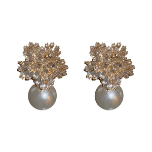 Elegant gold flower earrings with sparkling zircons and white pearls on white background