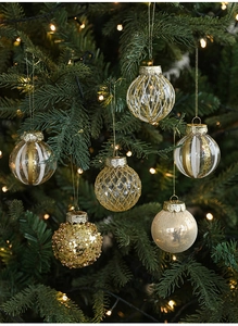 Close-up of assorted gold Christmas ornaments with glitter and stripes on tree