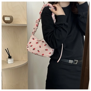 Detail of pink corduroy shoulder bag with red strawberry prints and ruched handle design