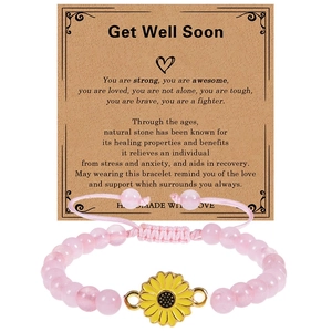 Detailed shot of pink natural stone bracelet with sunflower charm on a Kraft paper card