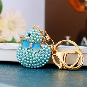 Close-up of light blue pearl duck keychain with golden metal ring and lobster clasp detail