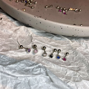 Macro shot of colorful heart and round zircon stud earrings with secure screw ball back