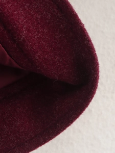 Nahaufnahme von weinrotem Tweed-Stoff mit detaillierter Textur und Premium-Nähten