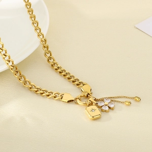 Detailed close-up of golden multi-element necklace with clover pendant and rhinestones