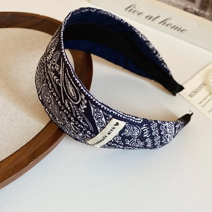 Détail d'un serre-tête en tissu cachemire bleu foncé avec étiquette faite main sur bois