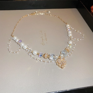 Détail du pendentif cœur doré avec strass en cristal et perles blanches