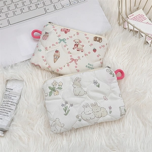 Detail of quilted mini pouches with cute cartoon rabbit and bear prints on soft white fabric