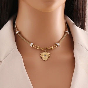 Detail of golden heart necklace with evil eye pendant on mesh chain with sparkling charms