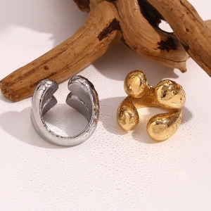 Détail de boucles d'oreilles texturées lave argentées et dorées sur surface humide