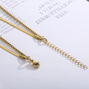 Macro detail of golden double-layer snake and box chains with lobster clasp and extender