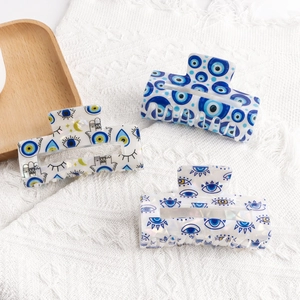 Three-piece evil eye patterned claw clips on white lace for Mediterranean hair styling