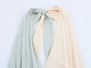 Detailed view of two-tone mint green and beige pleated neck tie on a summer dress