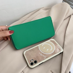 Long green faux leather zipper wallet with pebble texture shown next to a smartphone