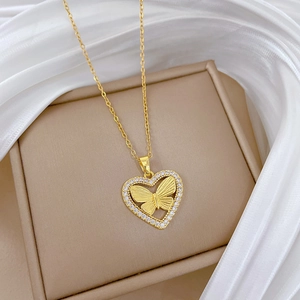 Detail of gold heart pendant with crystal border and butterfly relief on silk fabric