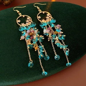 Detail showing vintage star fringe earrings with blue and purple beads on velvet