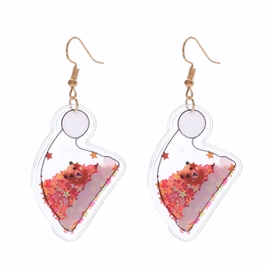 Detail of Christmas tree bell earrings with red stars and bear sequins inside acrylic