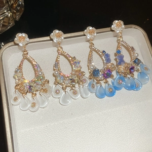 Macro detail of luxury floral drop earrings with pearls and crystals on beige velvet box