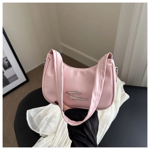 Detail of pink crescent bag with silver star buckle held against modern home backdrop