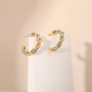 Two-tone gold and silver twisted rope hoop earrings on a minimalist white stand