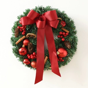 Classic green Christmas wreath with large red bow, pine cones and berries on white backdrop