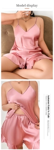 Detailed view of pink satin pajama set featuring V-neck lace top and ruffled hem shorts