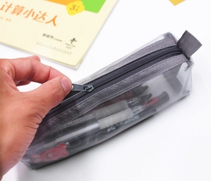 Detail of opening gray mesh pencil case with smooth zipper on white desk surface