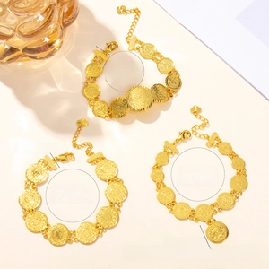Detailed view of golden coin bracelets with engraved discs and lobster clasp closure