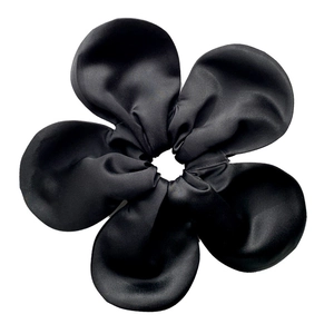 Detail of oversized black satin scrunchie showing glossy fabric texture and floral folds
