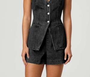 Détail d'un ensemble deux pièces en jean noir délavé avec gilet boutonné et short assorti