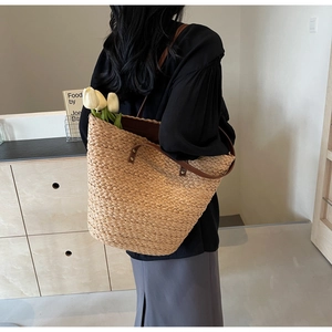 Detailed back view of large straw tote bag with brown leather straps for daily use