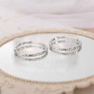 Detail showing hand-hammered texture on silver titanium steel hoop earrings on a mirror