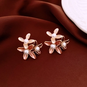 Detail of flower stud earrings featuring pink enamel petals and white pearls on velvet