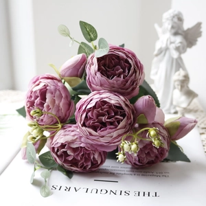 Close-up of artificial purple pink peony bouquet with green leaves in a romantic home setting