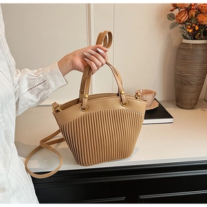 Detail of khaki pleated faux leather handbag with reinforced handle and gold hardware