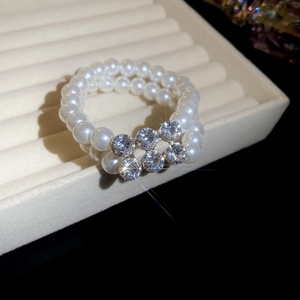 Macro shot of a double-row pearl ring with sparkling rhinestones on a beige display stand
