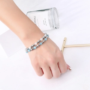 Detail view of double-layer beaded bracelet with silver metal and opal-like stones on wrist