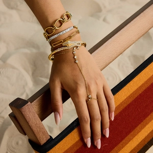 Gros plan sur un bracelet serpent doré et des bijoux superposés en acier inoxydable