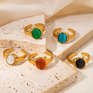 Detailed view of vintage gold rings with colorful oval stones on beige sandstone