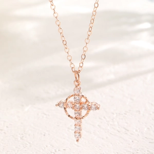 Macro detail of rose gold crown cross pendant with sparkling cubic zirconia crystals