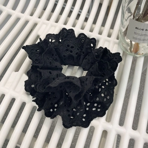 Detailed view of elegant black lace scrunchie with intricate floral eyelet embroidery