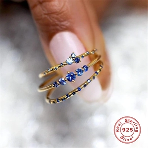 Close-up of three 925 sterling silver gold-plated rings set with blue zircons on a hand