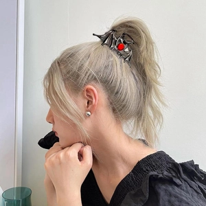 Detail of gothic black bat hair claw clip with red ruby stone on model's blonde hair