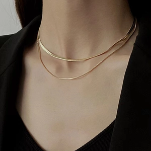 Elegant gold double-layered snake bone necklace worn by a model on black background