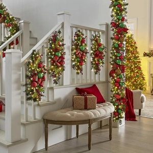 Illuminated Christmas staircase teardrop swags with red berries and plaid bows on white railing