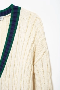 Detail of cable knit cardigan with green and blue striped V-neck and thick texture
